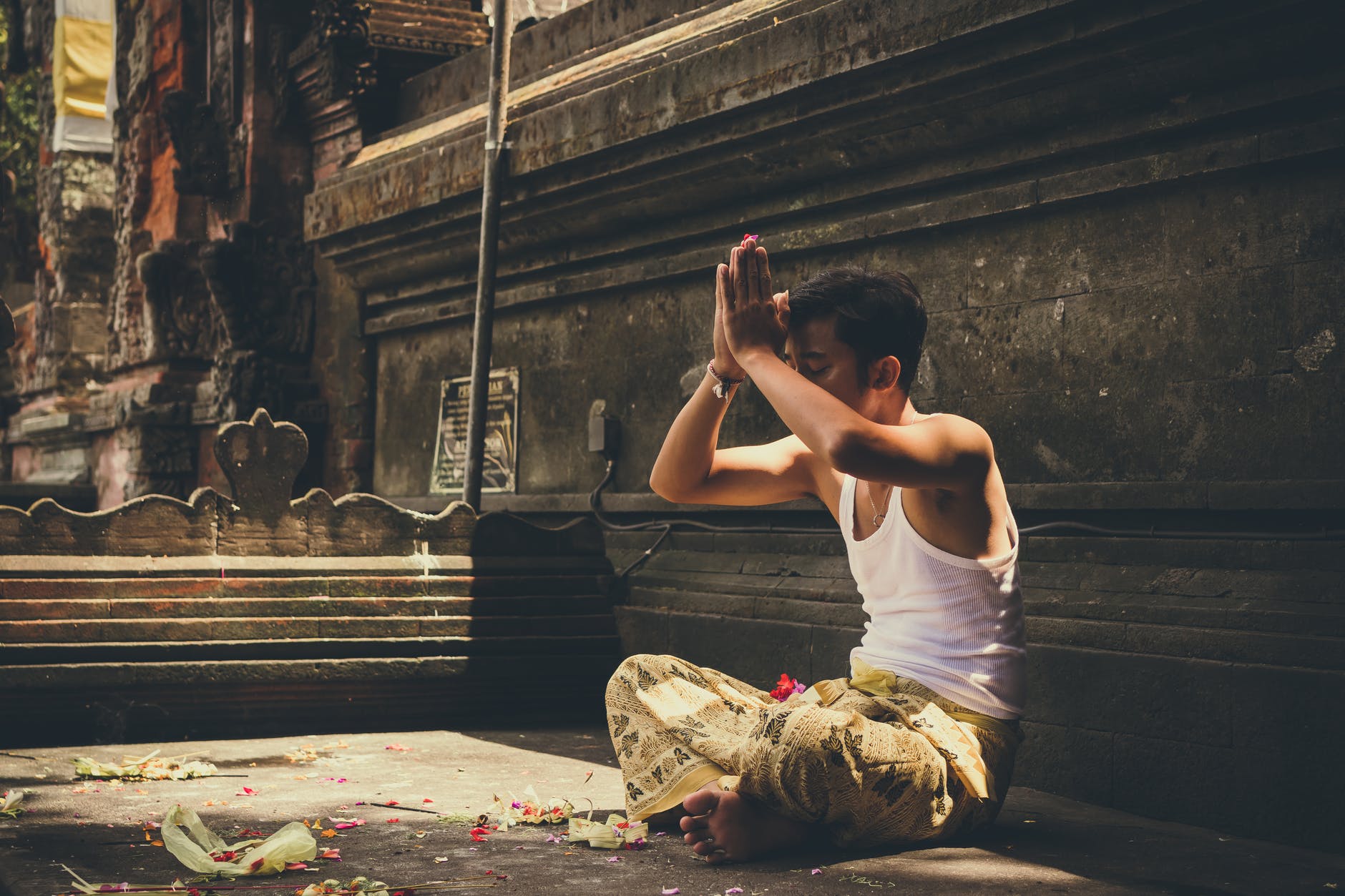 man wearing white tank top praying